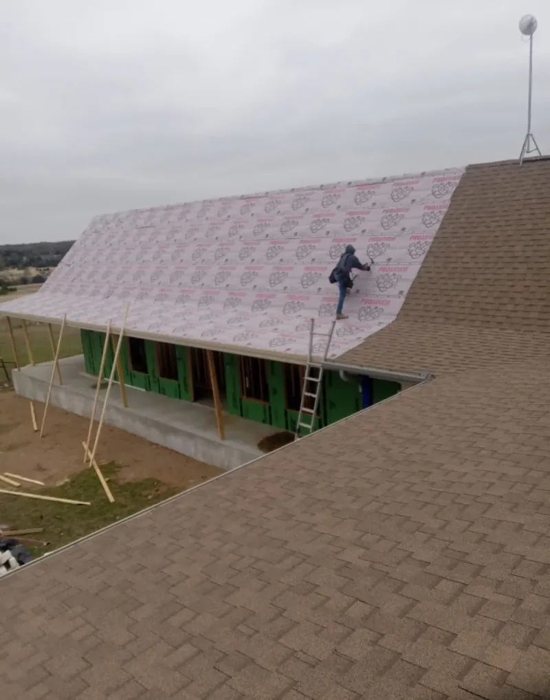 Worker preparing underlayment for a metal roof installation in Anderson